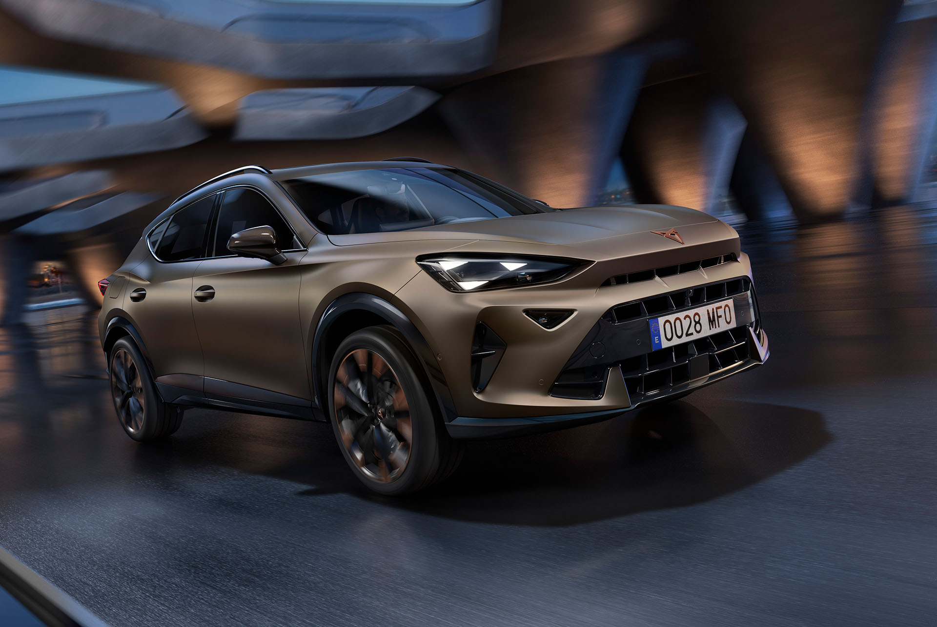 Nowa CUPRA Formentor 2024 w kolorze Century Bronze Matt podczas jazdy z rozdzielaczem momentu obrotowego. W tle rozmyta panorama i architektura.